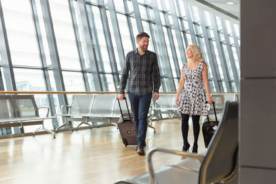 Travelling couple with suitcases walking in airport hallway