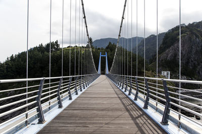 Hardanger bridge leading towards mountain against cloudy sky