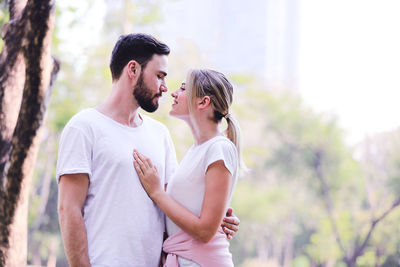 Young couple standing against trees