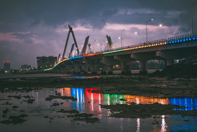 Illuminated bridge over river at night