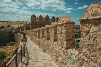 Pathway over old thick wall with battlement and large tower made of stone in avila, spain.