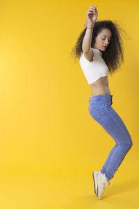Full length of young woman against yellow background