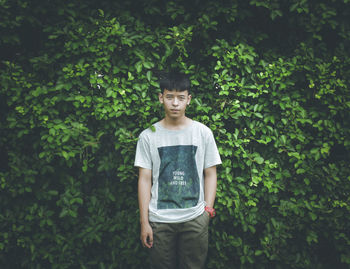 Portrait of young man while standing against plants