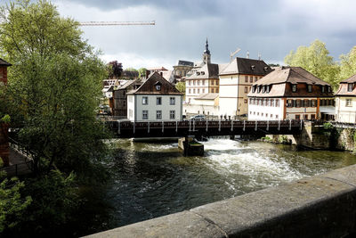 Buildings by river against sky