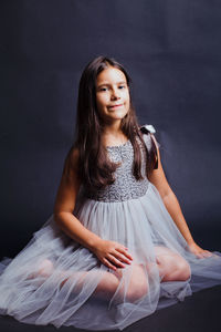 Girl kneeling against gray background