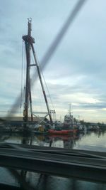 Cranes at riverbank against sky