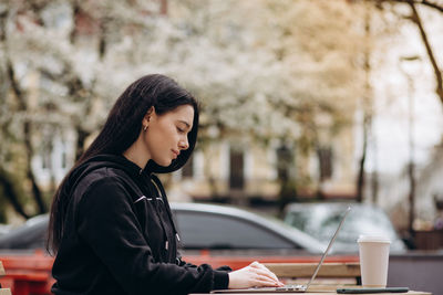 Young woman using laptop while sitting on table