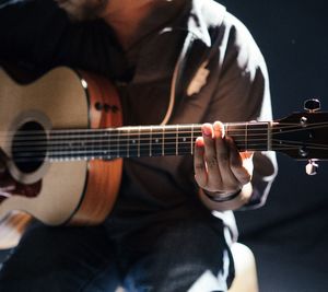 Midsection of man playing guitar