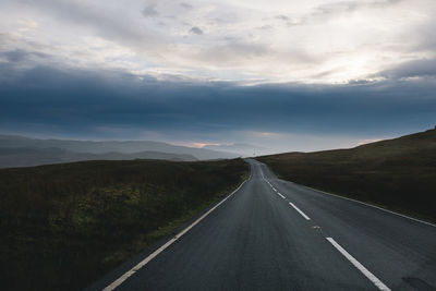 Road passing through landscape against dramatic sky