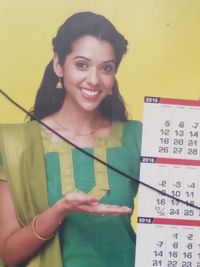 Portrait of a smiling young woman standing against wall