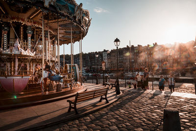 People at amusement park against sky in city