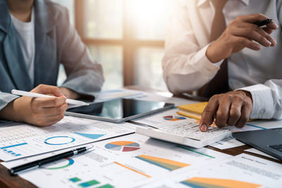 Midsection of business colleagues working on table