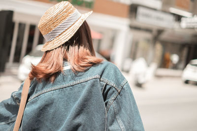 Rear view of woman with umbrella on street in city