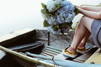 LOW SECTION OF WOMAN SITTING ON STAIRCASE BY PLANT