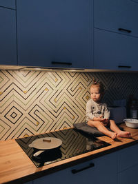 A little girl is sitting on a table in the kitchen