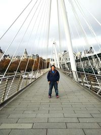Full length of man standing on golden jubilee bridge against cloudy sky