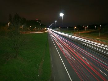 Light trails on bridge against sky at night