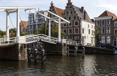 Bridge over canal by buildings in city against sky