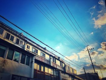 Low angle view of electricity pylon and buildings against sky