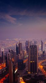 Illuminated buildings in city against sky at dusk