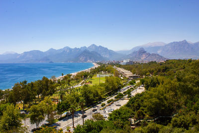 Scenic view of sea and mountains against clear blue sky