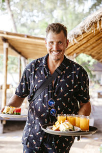 Portrait of smiling male tourist with breakfast in resort during vacation