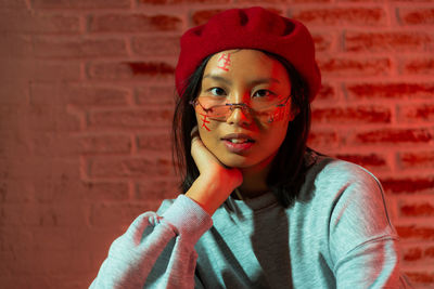 Portrait of young woman against wall