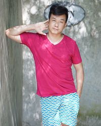 Portrait of young man standing by wall