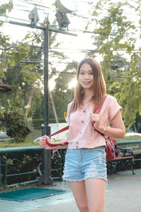 Portrait of smiling young woman standing against trees