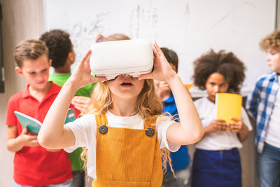 Cute girl using virtual reality simulator at classroom