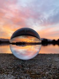 Close-up of crystal ball on beach against sky during sunset