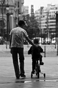 Rear view of father and son walking on street