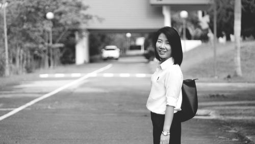 Portrait of a smiling girl standing on road in city