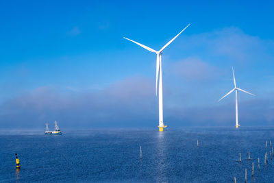 Wind turbines in sea against sky