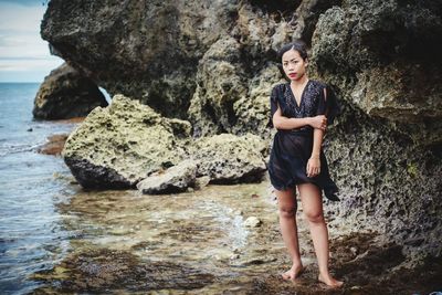 Full length portrait of young woman standing on rock