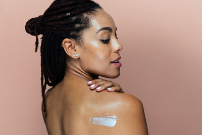 Close-up of shirtless young woman against white background