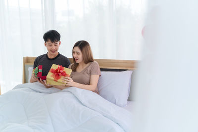 Young couple sitting on bed at home