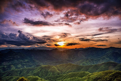 Scenic view of landscape against dramatic sky during sunset