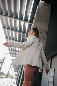 Portrait of young woman standing against wall