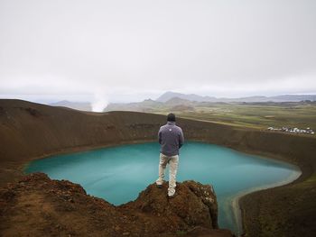 Rear view of man standing on mountain against sky