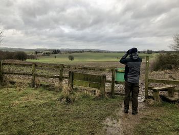 Rear view of man standing on field against sky