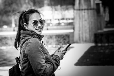 Portrait of woman using mobile phone while wearing sunglasses