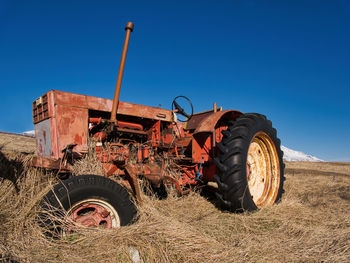 Tractor on field against clear blue sky