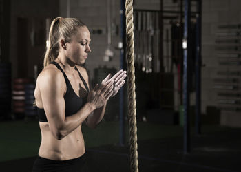 Side view of female athlete chalking hands before exercising in gym