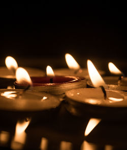 Close-up of illuminated candles against black background