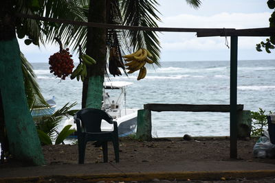 Chair on table by sea against sky