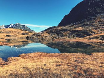 Scenic view of lake and mountains against clear blue sky