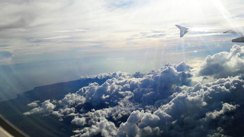 Cropped image of airplane flying over sea against clouds