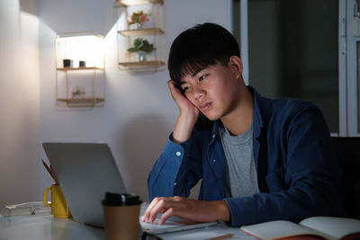 Young woman using phone while sitting on table