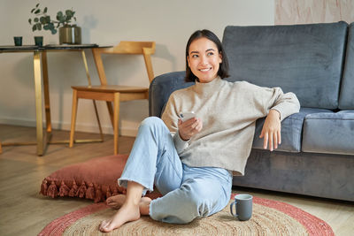 Portrait of young woman sitting on sofa at home